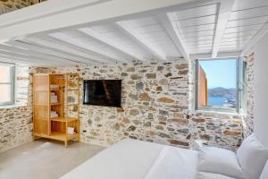 a bedroom with a stone wall and a bed and a tv at ArtdecoSyros Superior in Ano Syros