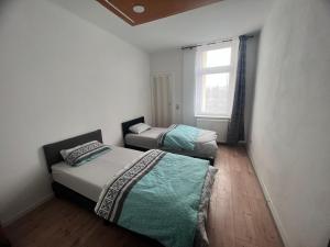 two beds in a small room with a window at Gera Apartment in Gera