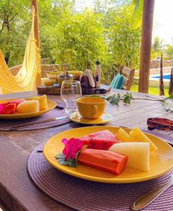 a table with a plate of cheese and fruit on it at Pousada Vila do Alto in Japaratinga