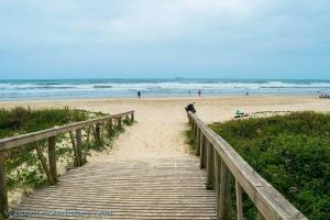 een houten promenade die leidt naar een strand met mensen bij Casa de férias familiar com linda vista à 300m da Meia Praia de Navegantes in Navegantes