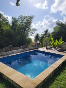 a swimming pool in a yard with chairs and trees at Pousada Vila do Alto in Japaratinga