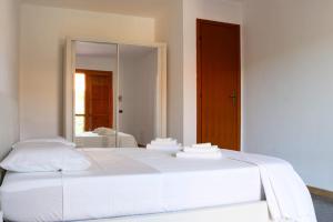 a white bed in a room with a mirror at Taverna Porto Conte in Porto Conte