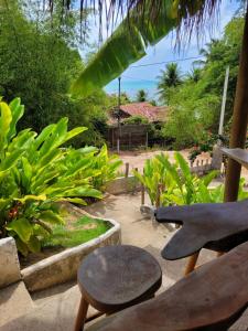 a patio with a table and a bench and plants at Pousada Vila do Alto in Japaratinga