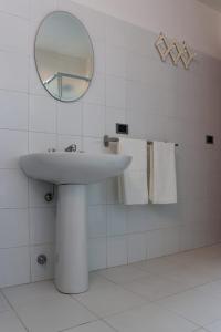 a white bathroom with a sink and a mirror at Taverna Porto Conte in Porto Conte