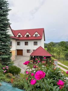 une grande maison avec un toit rouge et des fleurs roses dans l'établissement Pokoje u Jasia i Małgosi, à Skawa