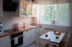 a kitchen with white cabinets and a table and chairs at Apartament w Alejce in Rabka