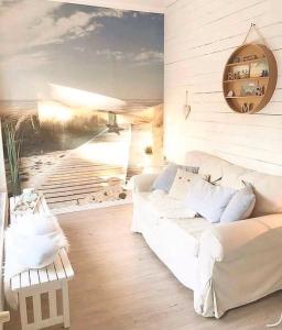 ein Wohnzimmer mit einer weißen Couch und einem Gemälde eines Strandes in der Unterkunft Deichhaus No.5 in Büsum