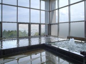 a bath tub with water in a room with windows at Kannawa Onsen Zekkei no Yado Sakuratei - Vacation STAY 50727v in Beppu