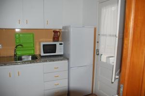 a kitchen with a white refrigerator and a microwave at A Casa da Maria in Tavira