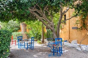 a group of blue chairs and tables under a tree at Vagia Traditional, Aegina Island in Vaia