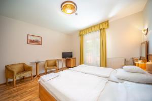 a hotel room with two beds and a table and chairs at Nefelejcs Hotel in Mezőkövesd