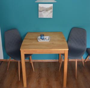 una mesa de madera con 2 sillas y una taza. en Jolle im Schiffehaus, en Wangerland