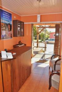 a kitchen with orange walls and a bar with a view at Pousada Encanto dos Cânions in Cambara do Sul