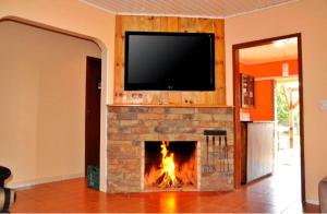 a living room with a fireplace with a tv above it at Pousada Encanto dos Cânions in Cambará