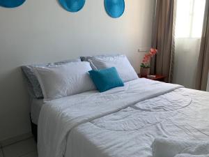 a white bed with a blue pillow on it at Habitación en apartamento compartido al frente del cc Unico in Barranquilla