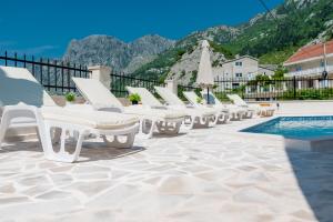 a row of white lounge chairs next to a swimming pool at Boka bay in Kotor