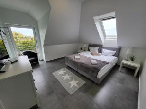 a bedroom with a bed and a desk and windows at Villa Bella Sauna & Jacuzzi in Międzywodzie