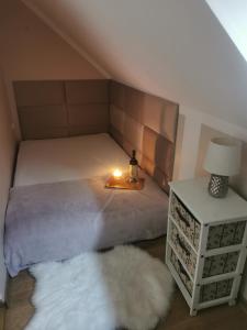 a bedroom with a bed with a candle and a white rug at Zakątek u Natalii in Lubawka