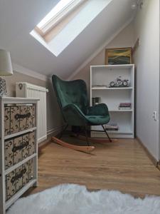 a room with a green chair and a book shelf at Zakątek u Natalii in Lubawka