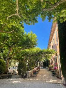 un arco su una strada con panchine e alberi di Le Mas des Grès & Sous les Platanes a Lagnes