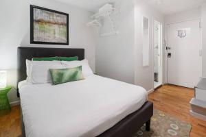 een slaapkamer met een groot wit bed met groene kussens bij Elevate Apartment at Times Square - Cozy Studio in Times Square and Nearby Restaurants in New York