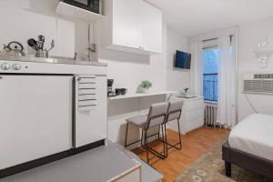 een witte keuken met 2 stoelen en een bed bij Elevate Apartment at Times Square - Cozy Studio in Times Square and Nearby Restaurants in New York