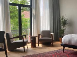 een slaapkamer met 2 stoelen, een bed en een raam bij Boutique Hotel Marie Marie in Dendermonde