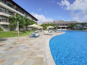 a resort with a swimming pool and tables and chairs at CoHost Flat BeachClass EcoLife 104G in Porto De Galinhas