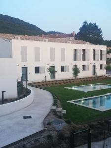 een groot wit gebouw met een zwembad en een tuin bij Le Silence Du Ventoux in Malaucène