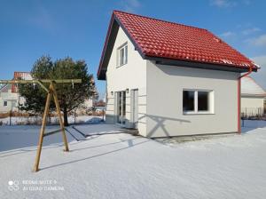 una casa blanca con techo rojo y aro de baloncesto en Morskie Zacisze, en Łeba
