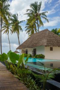a resort with a swimming pool and palm trees at Savera Beach Houses in Jambiani
