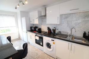 ロンドンにあるLondon Central Modern Apartment Charltonのキッチン(白いキャビネット、洗濯機、乾燥機付)