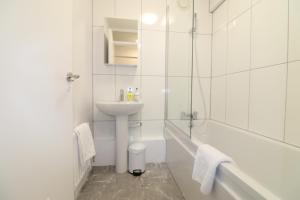 London Central Modern Apartment Charlton في لندن: حمام أبيض مع حوض وحوض استحمام