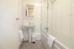 a white bathroom with a sink and a bath tub at London Central Modern Apartment Charlton in London