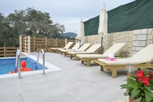 a row of lounge chairs next to a swimming pool at Villa Michalis in Liapades
