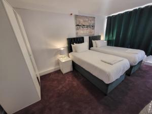 two beds in a room with green curtains at London Central Modern Apartment Charlton in London