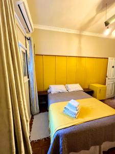 a room with two beds with yellow walls at Suítes no centro histórico in Petrópolis +5 photos