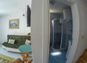 salon z zieloną kanapą i prysznicem w obiekcie Sirinevler Apart IMROS w mieście Gokceada