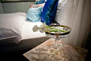 Eine Glasvase mit einer Blume auf einem Tisch neben einem Bett in der Unterkunft Hotel TraumRaum - "SELF CHECK IN" in Heilbronn