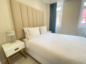 a bedroom with a large white bed and a night stand at Bonneville Setúbal II in Setúbal