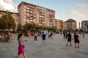 a group of people walking around a plaza with buildings at Etern Stays IEG - Pristine Apartment in Prishtinë