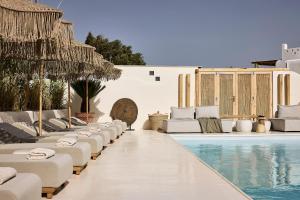 a pool with chaise lounges and chairs next to a resort at Sharm Hotel Mykonos in Mýkonos City