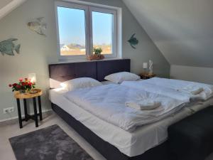 a bedroom with a large bed with two windows at Robson Beach I Sauna, Jacuzzi in Międzywodzie
