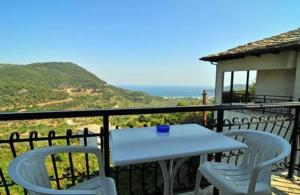 a white table and chairs on a balcony with the ocean at Chrissafis Hotel in Panagia