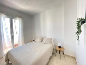 Un dormitorio blanco con una cama grande y una mesa en Townhouse w/sea view & garden, en Estepona