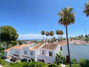 an aerial view of a white house with palm trees at Townhouse w/sea view & garden in Estepona