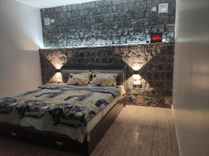 a bedroom with a bed with a stone wall at Sunrise Chalet شالية الشروق الجبل الاخضر in Duwaykhīlah