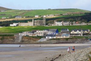 a group of people on a beach with a castle in the background at ONeills Apartments in Ballyheigue
