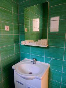 W wyłożonej zielonymi kafelkami łazience znajduje się umywalka i lustro. w obiekcie Apartments & Rooms Marinka w mieście Zadar