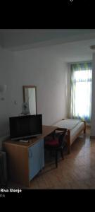 1 dormitorio con 1 cama y escritorio con TV en Hotel Riva, en Resen